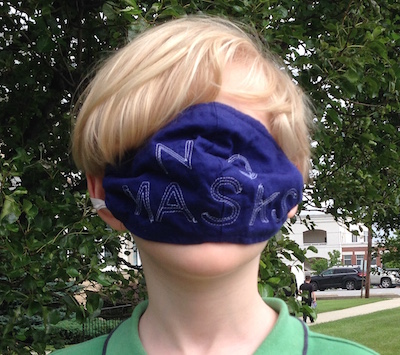Boy wearing mask over eyes that reads "NO MASKS"